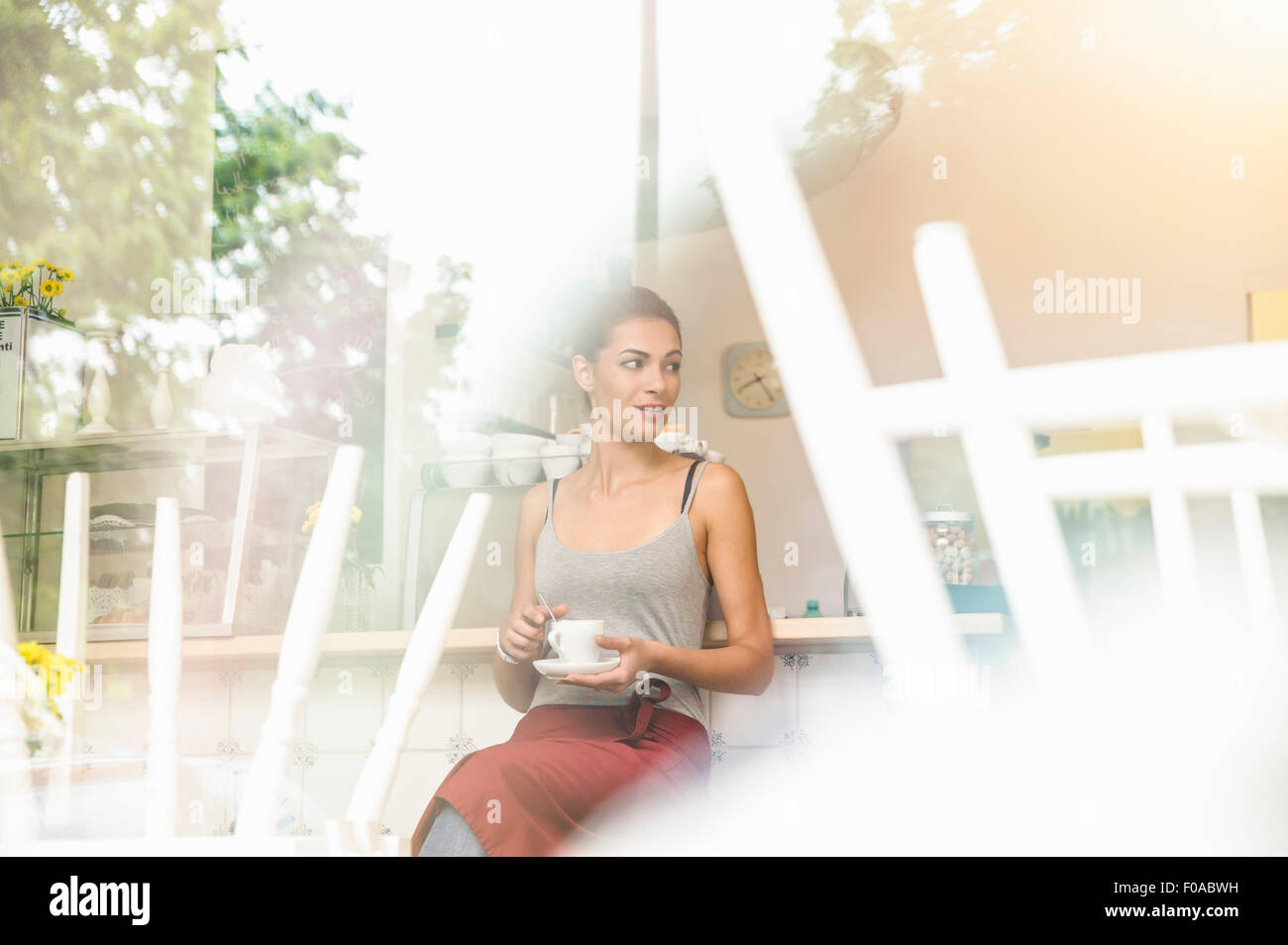 Young waitress sitting in cafe, view through window Stock Photo