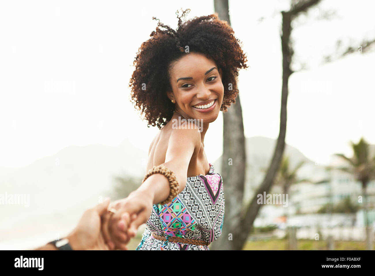 Young woman holding boyfriends hand at beach, Rio De Janeiro, Brazil Stock Photo
