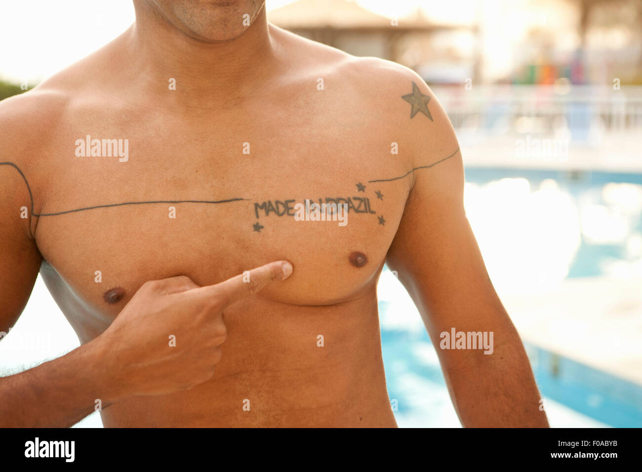 Cropped shot of man pointing to chest tattoo at hotel swimming pool, Rio De Janeiro, Brazil Stock Photo