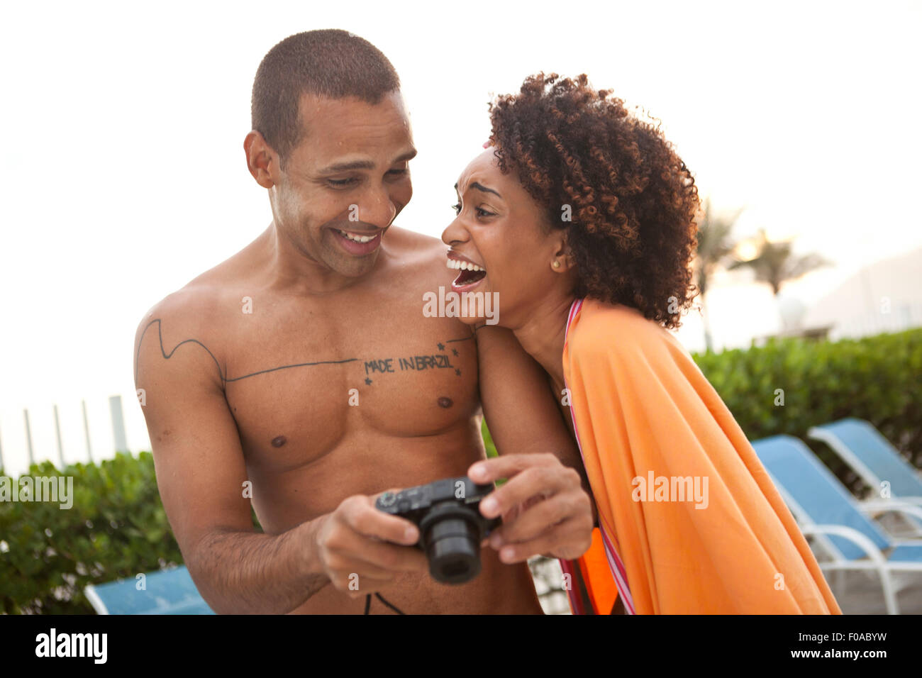 Couple laughing at photographs on digital camera at hotel poolside, Rio De Janeiro, Brazil Stock Photo