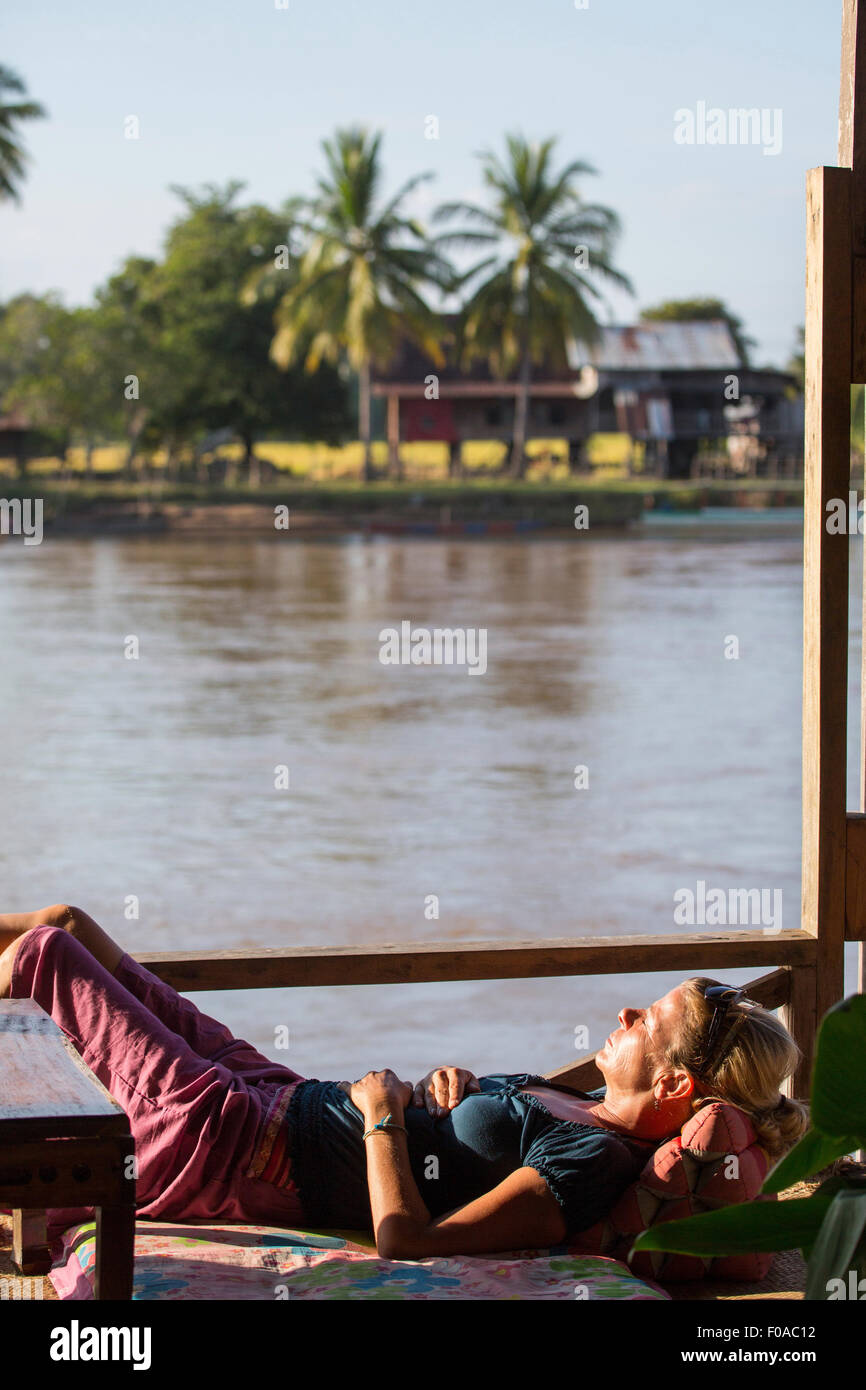 Female tourist sunbathing on Mekong houseboat, Don Det, Laos Stock Photo