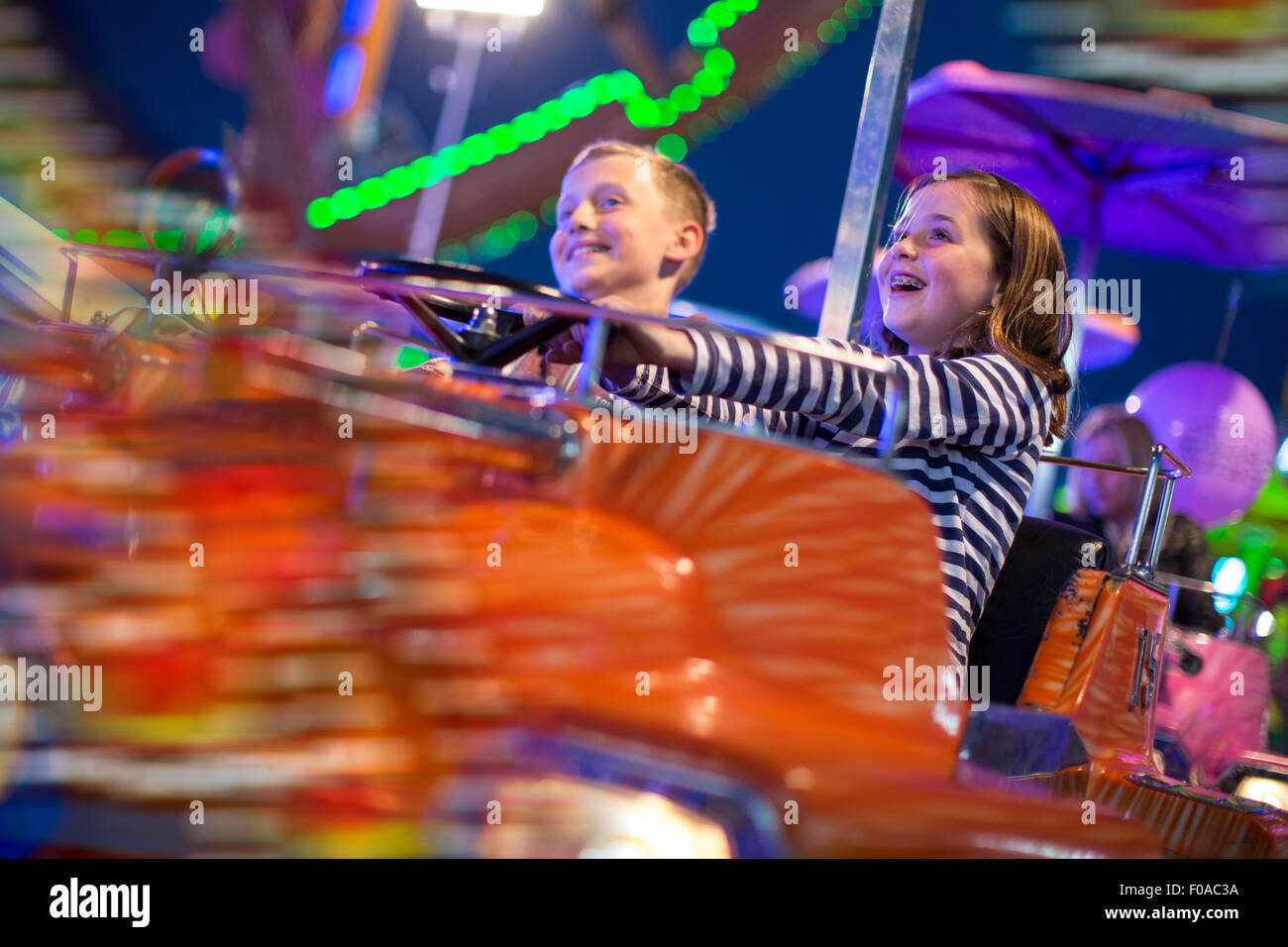 Brother and sister on fairground ride at night Stock Photo