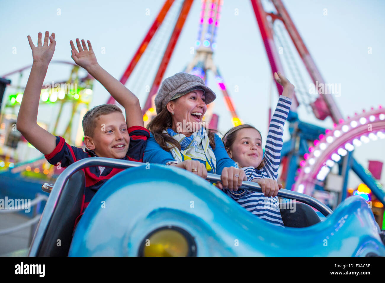 Mature woman with son and daughter on fairground ride Stock Photo