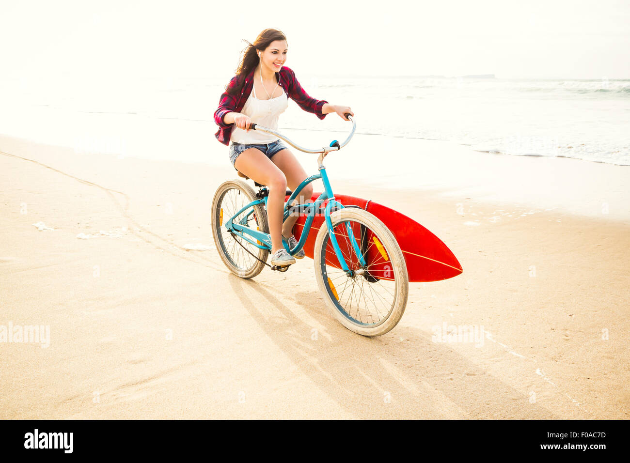 Surfer young woman riding her bicycle on the beach Stock Photo - Alamy