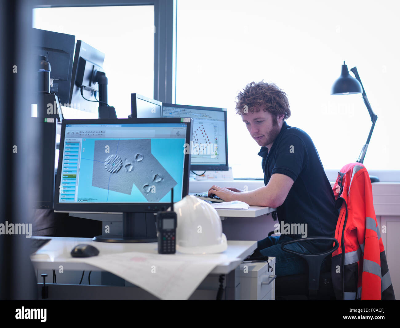 Offshore windfarm engineer working at desk in office Stock Photo