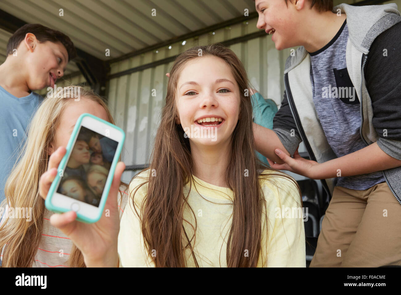 Girl holding up smartphone selfie of friends in shelter Stock Photo
