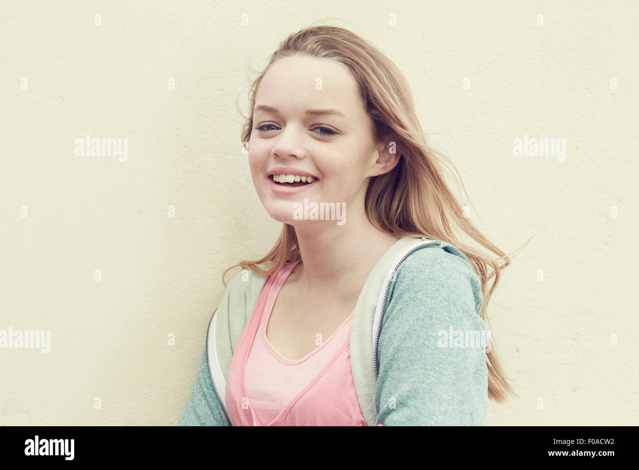 Portrait of smiling girl with long blond hair in front of wall Stock ...