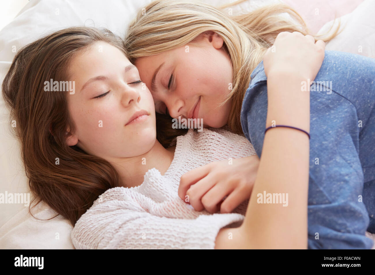 Two girls lying on bed with eyes closed Stock Photo