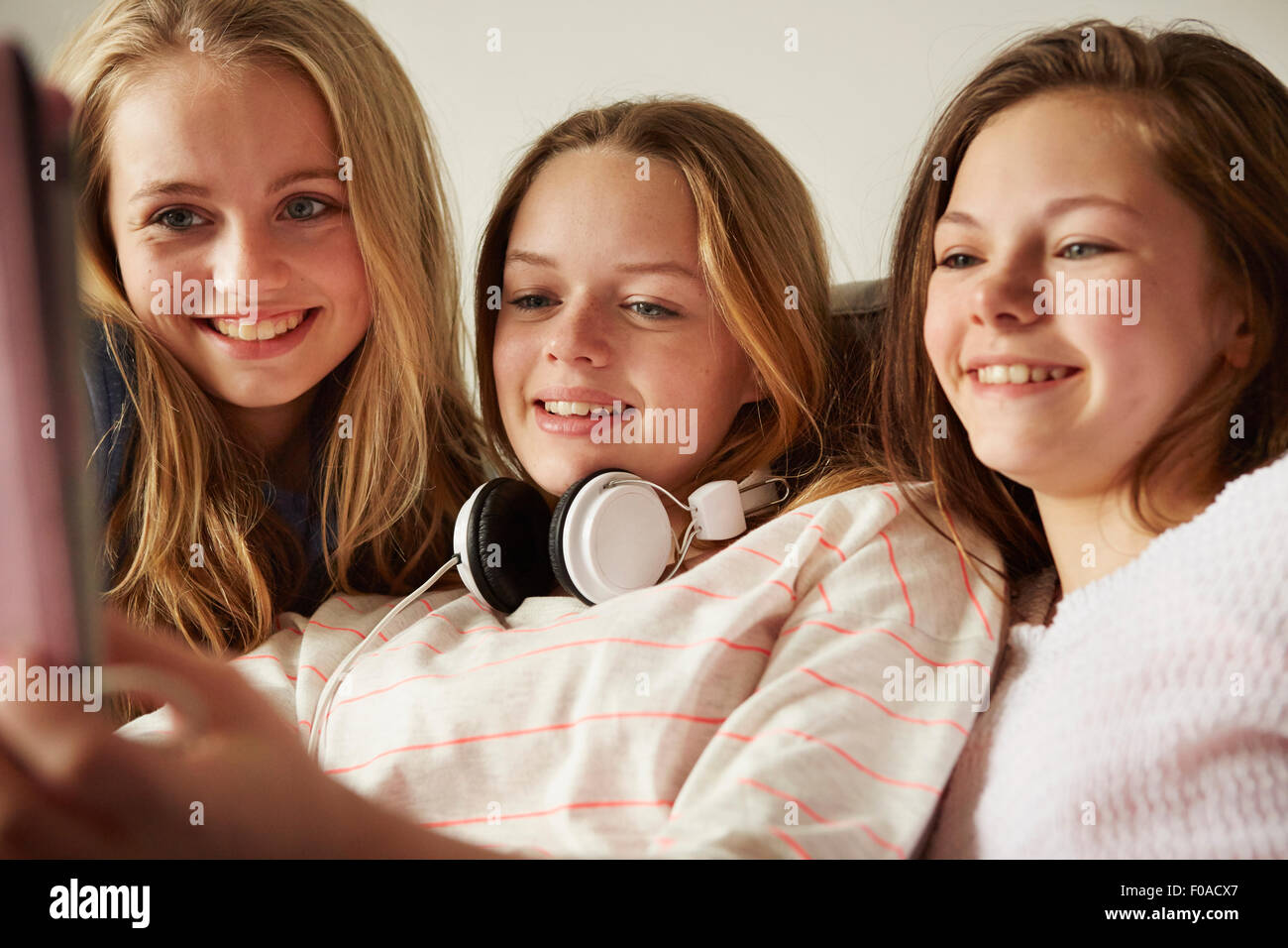 Three girls on sofa using digital tablet Stock Photo