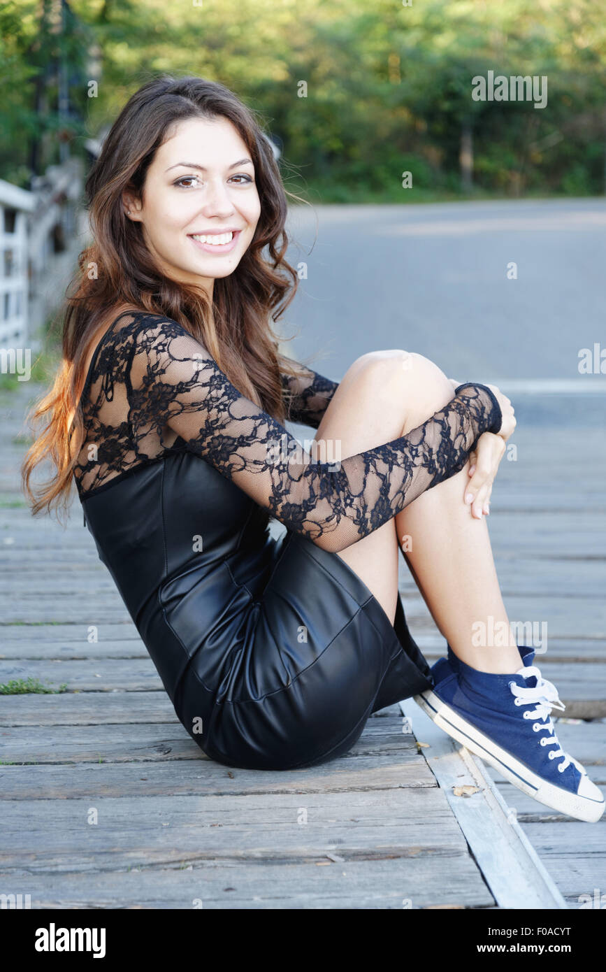 Portrait of a young woman sitting holding knees smiling at camera Stock Photo