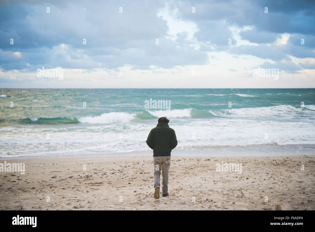 Rear view of man on windy beach, Sorso, Sassari, Sardinia, Italy Stock Photo