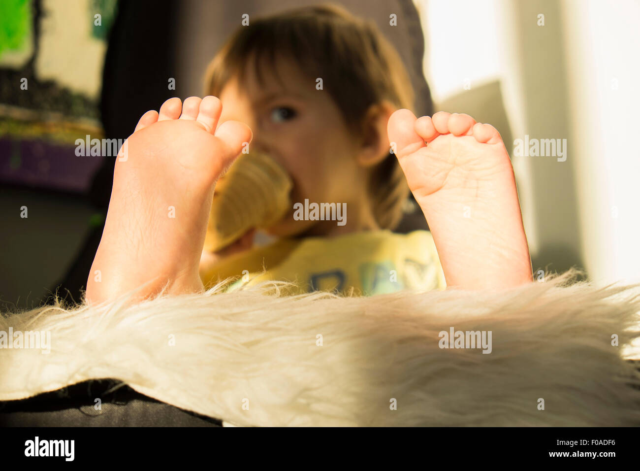 Young boy drinking from beaker, focus on feet Stock Photo