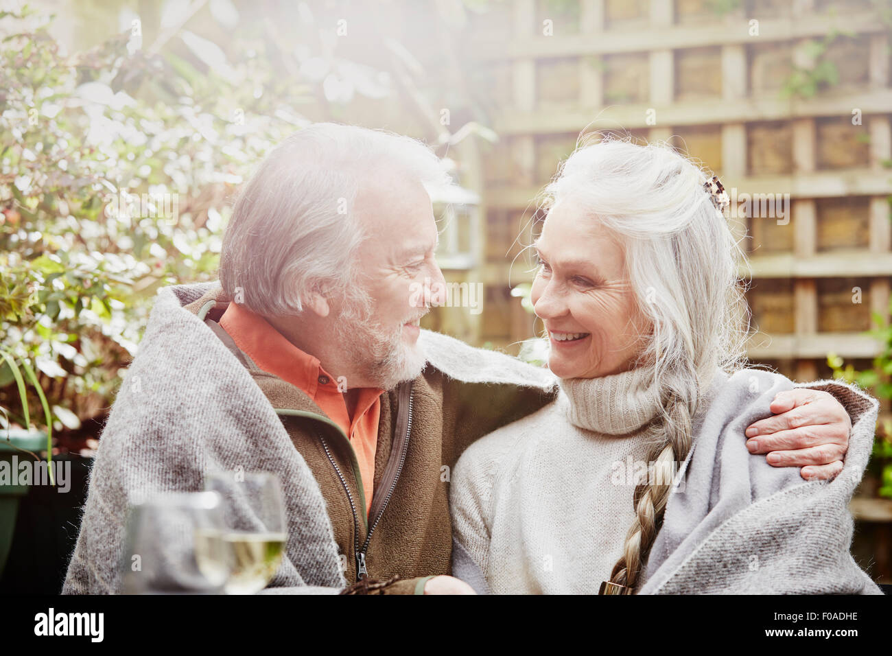 Senior couple wrapped in blanket in garden Stock Photo