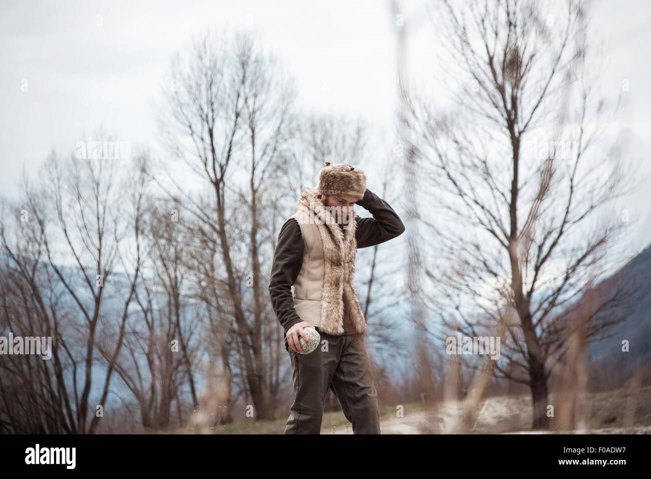 Mid adult man wearing trapper hat by trees Stock Photo