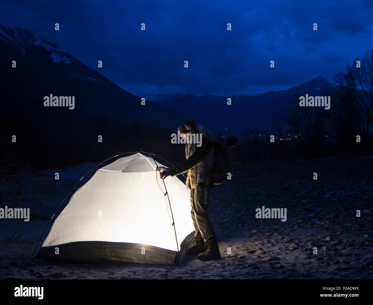 Man by tent illuminated at night, Premosello, Verbania, Piedmonte, Italy Stock Photo