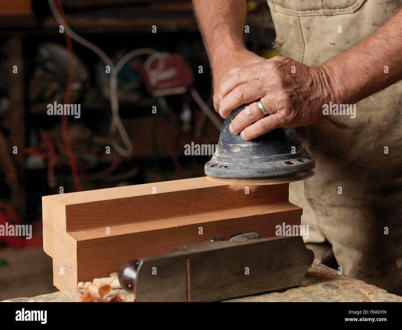 Boat builder sanding wood in workshop Stock Photo