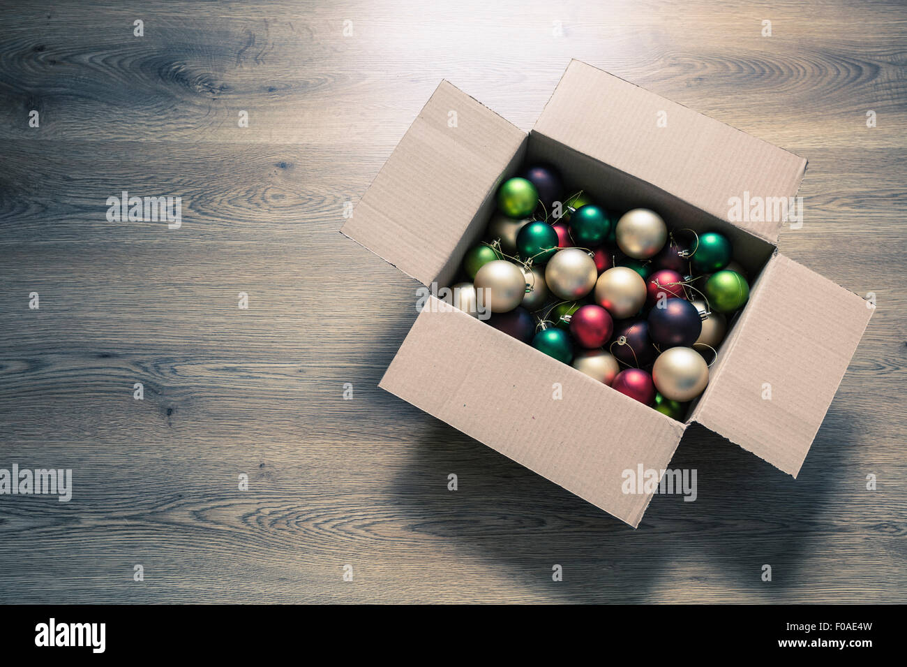 Christmas baubles in cardboard box on floor, high angle Stock Photo