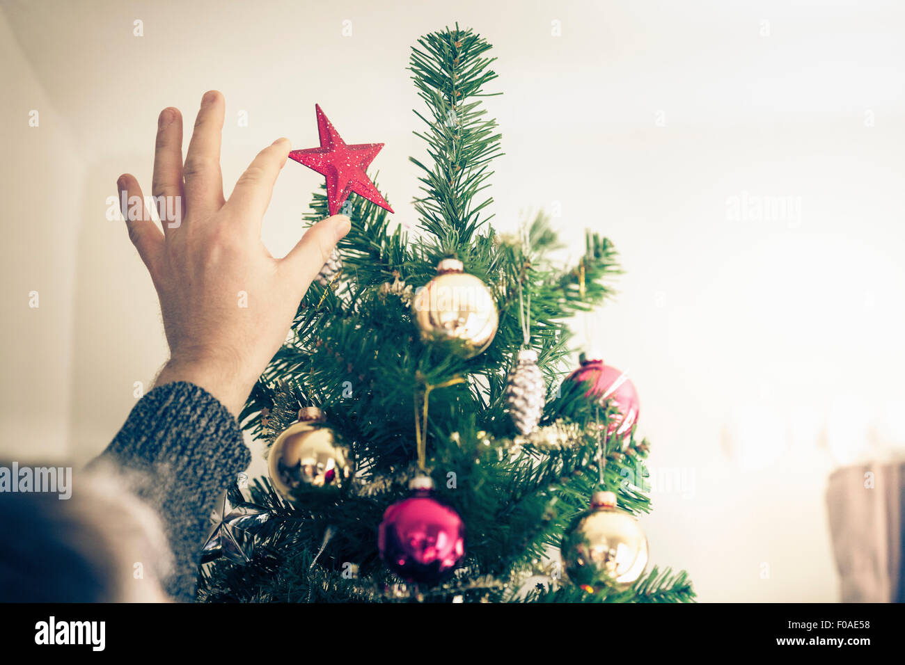 Person putting star on christmas tree Stock Photo