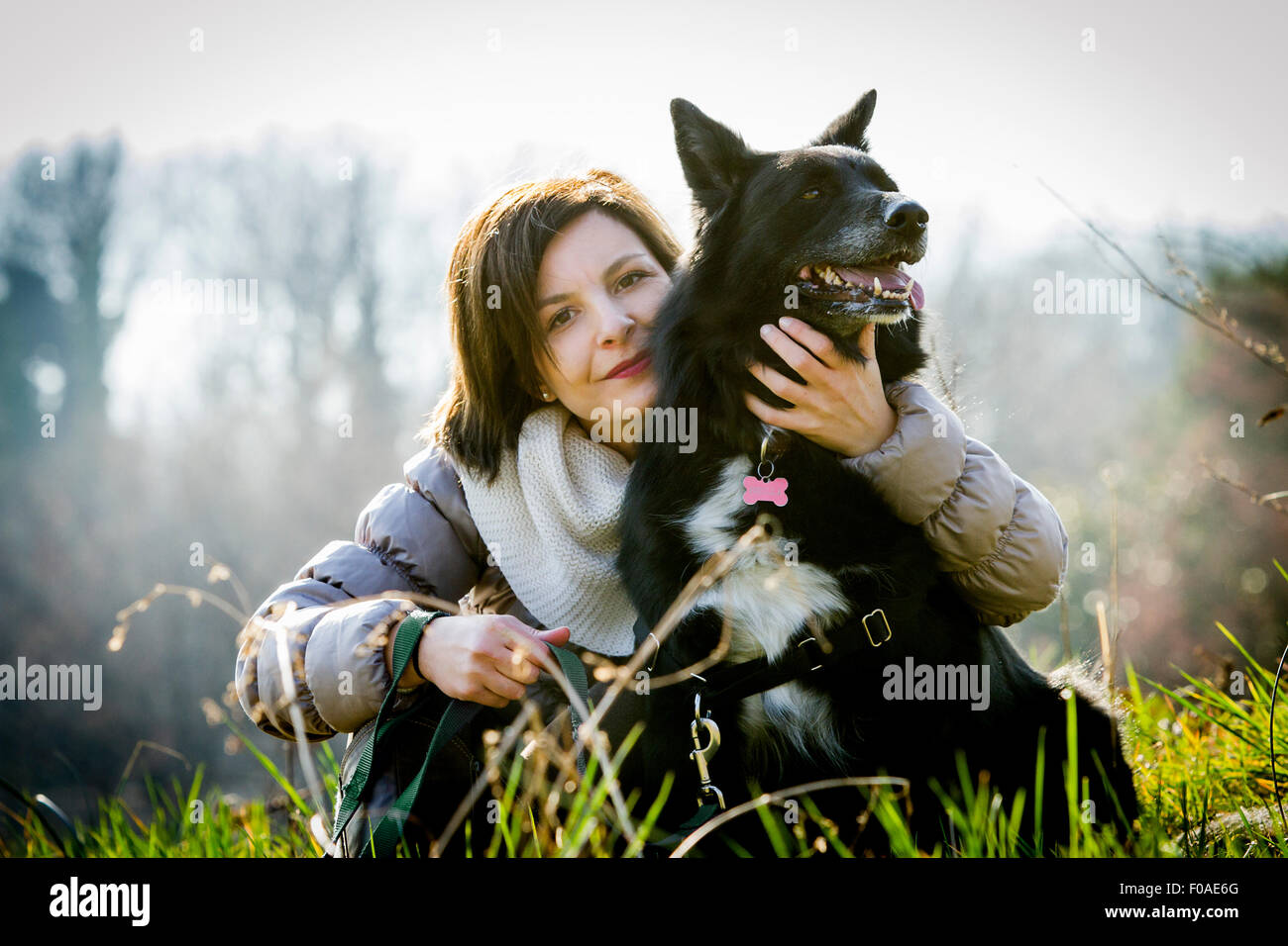 Portrait of mid adult woman with arm around her dog in field Stock Photo