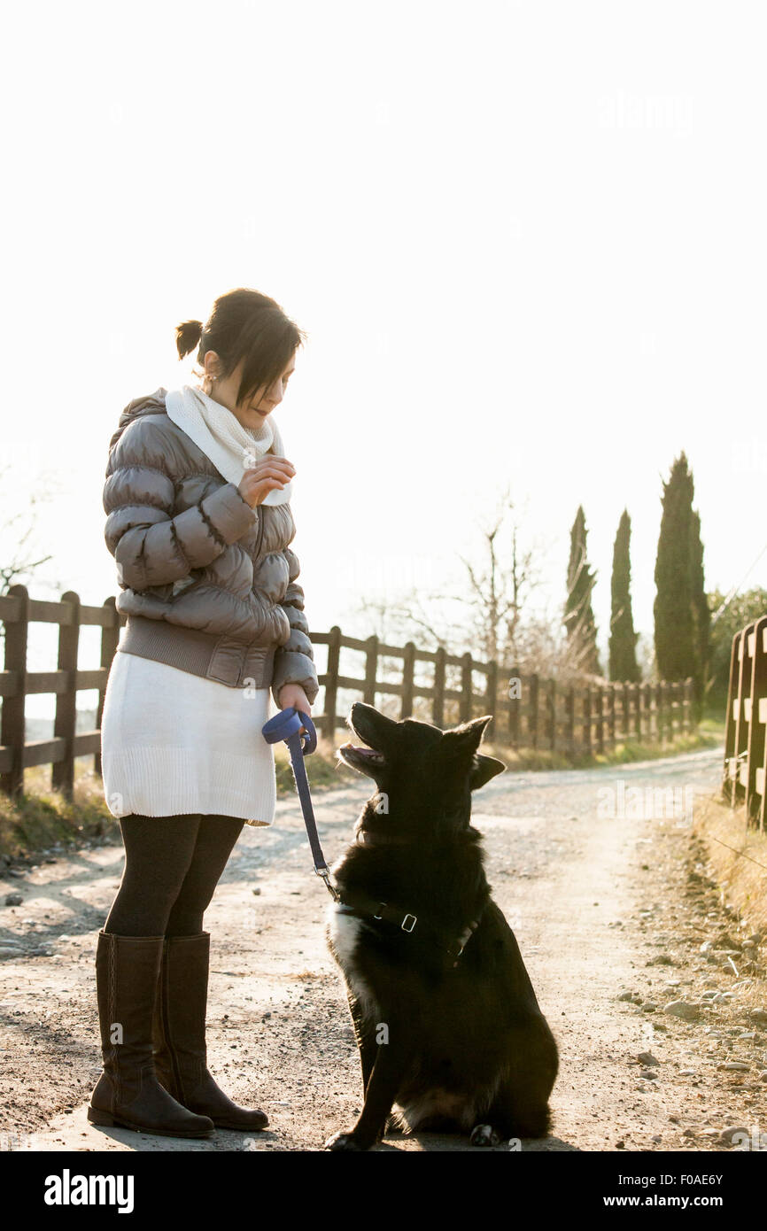 Mid adult woman obedience training her dog on rural road Stock Photo