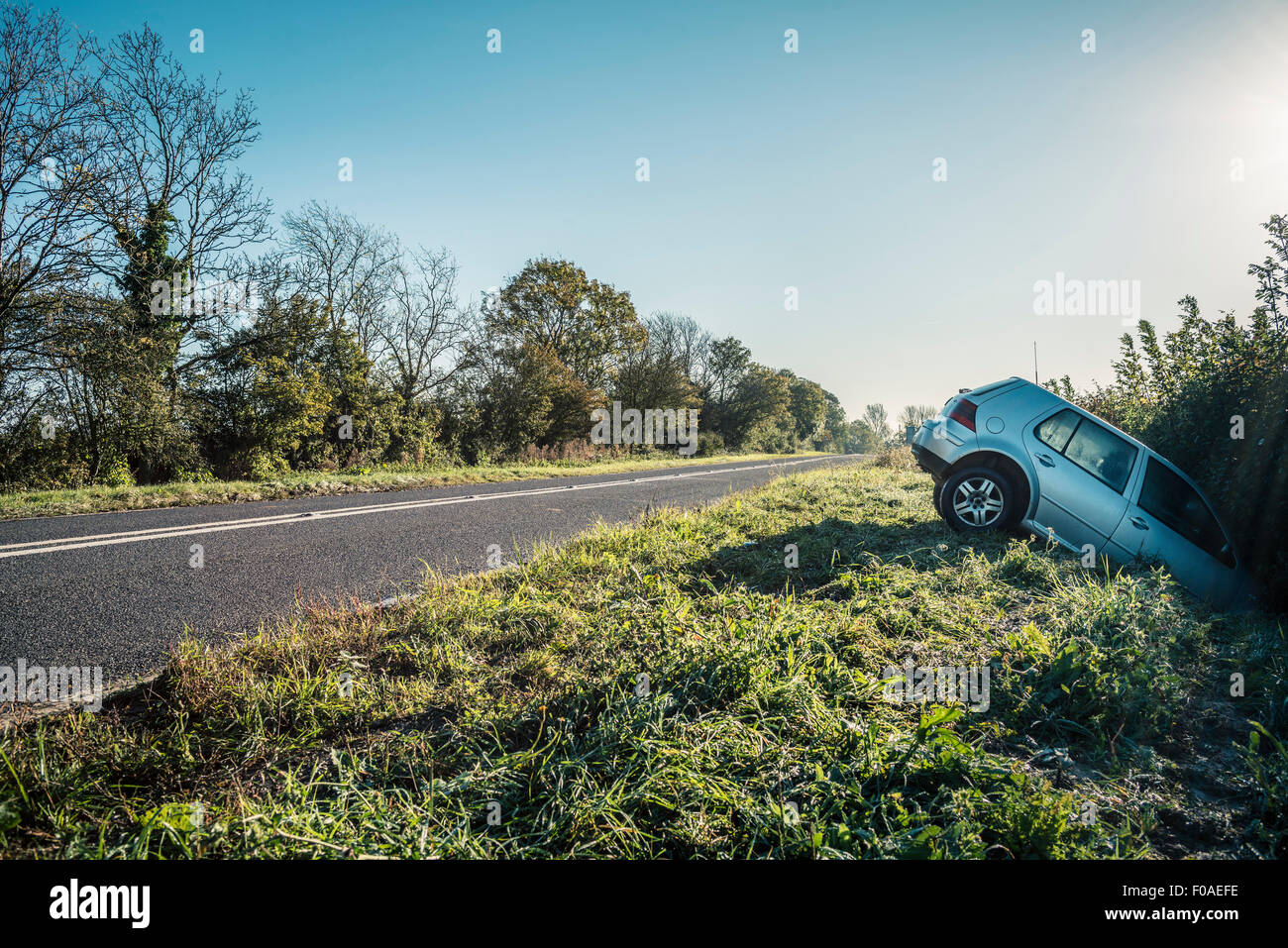 Car sticking out of hedge on rural highway roadside Stock Photo