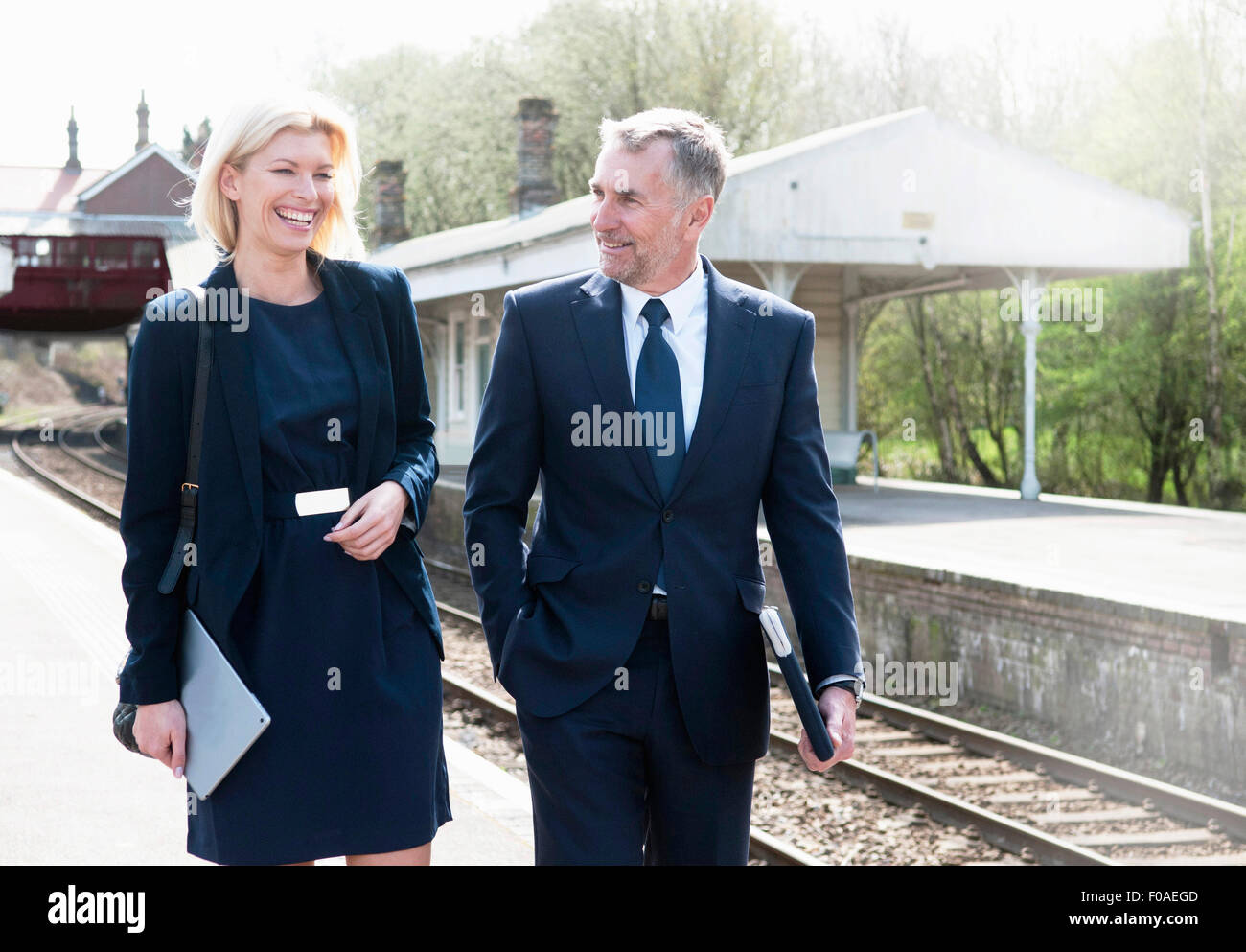 Businessman and woman talking on railway platform Stock Photo