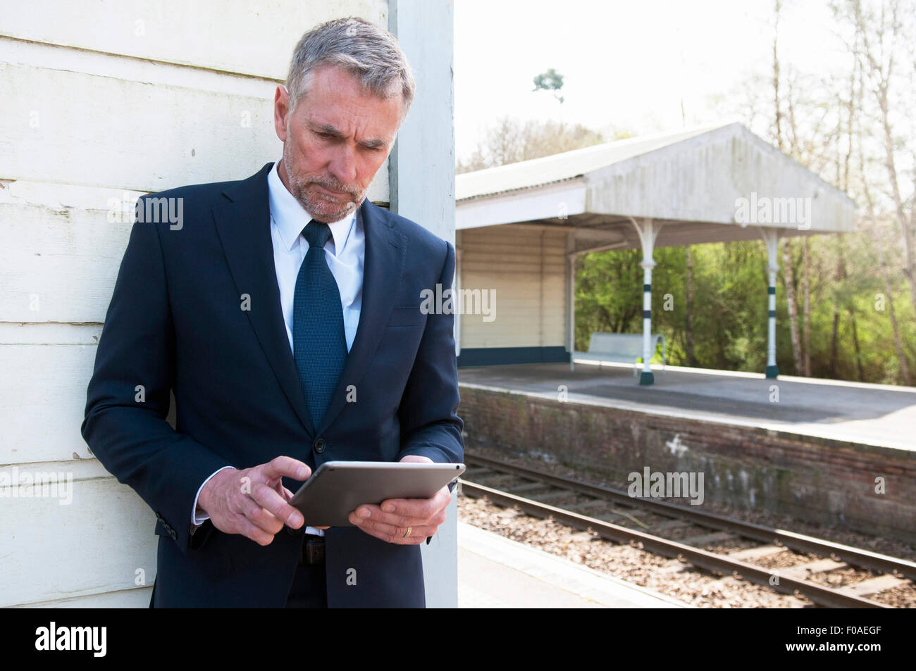 Businessman using digital tablet on railway platform Stock Photo