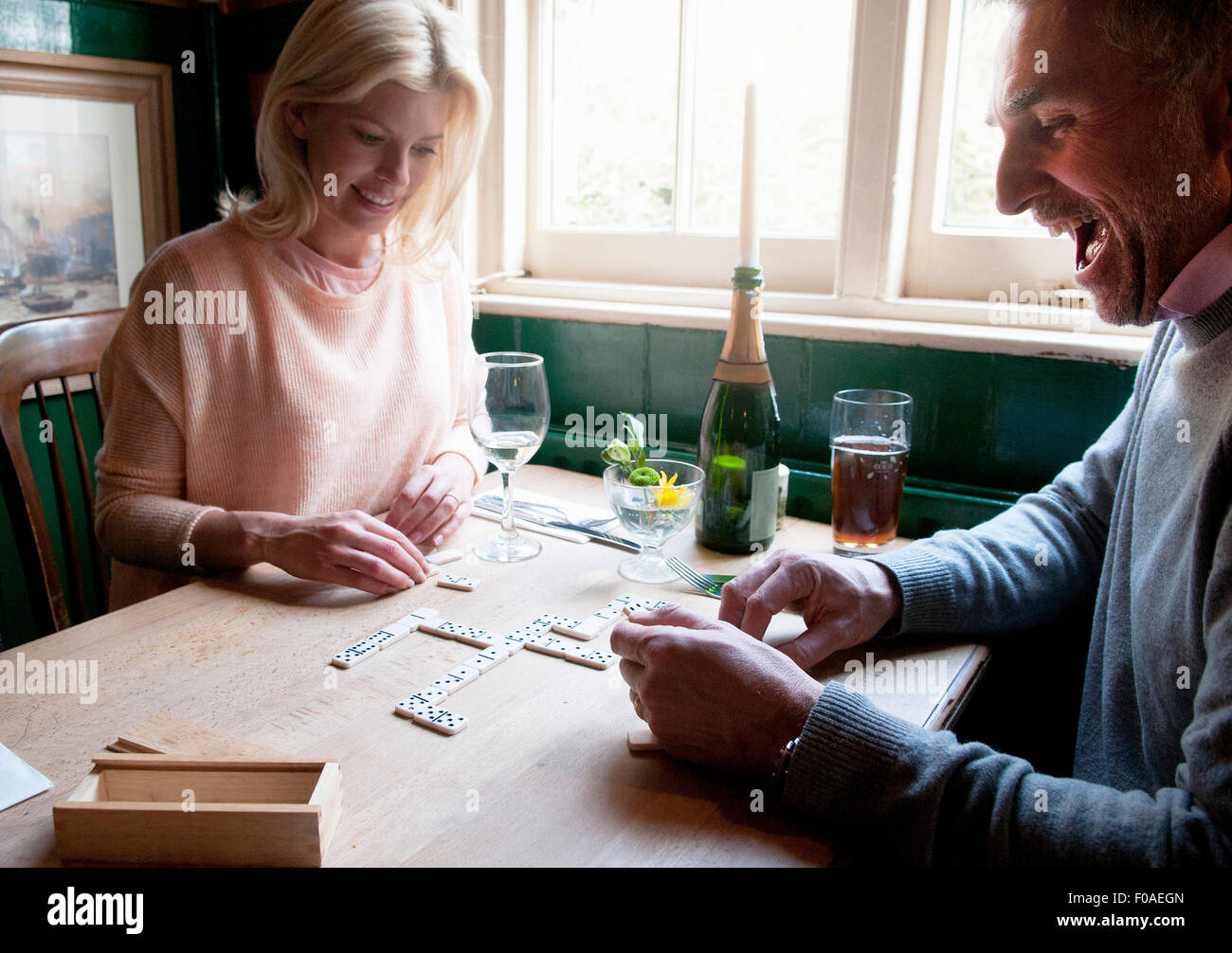 Couple drinking and playing dominoes in pub Stock Photo