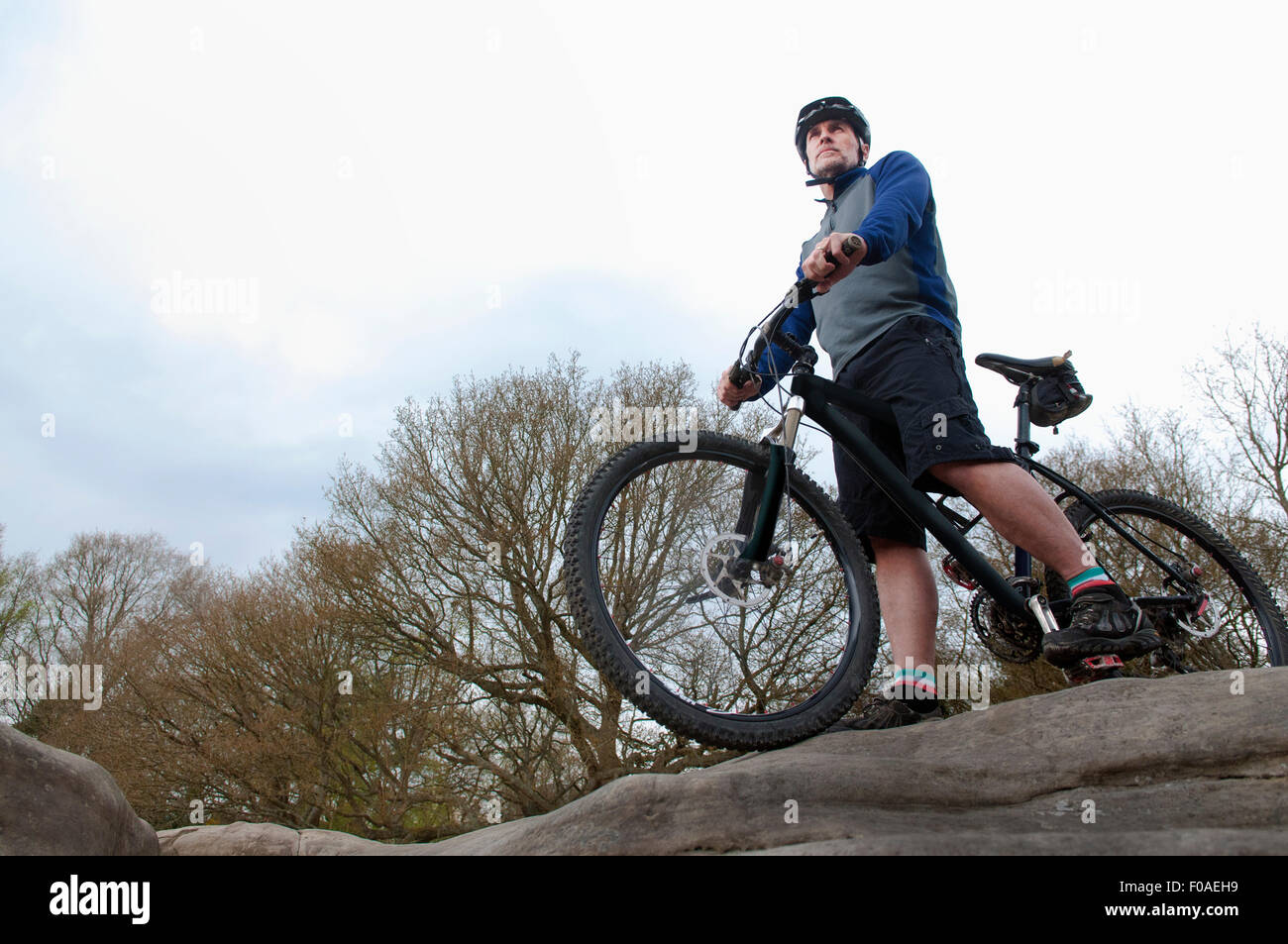 Mature male mountain biker looking out from rock formation Stock Photo