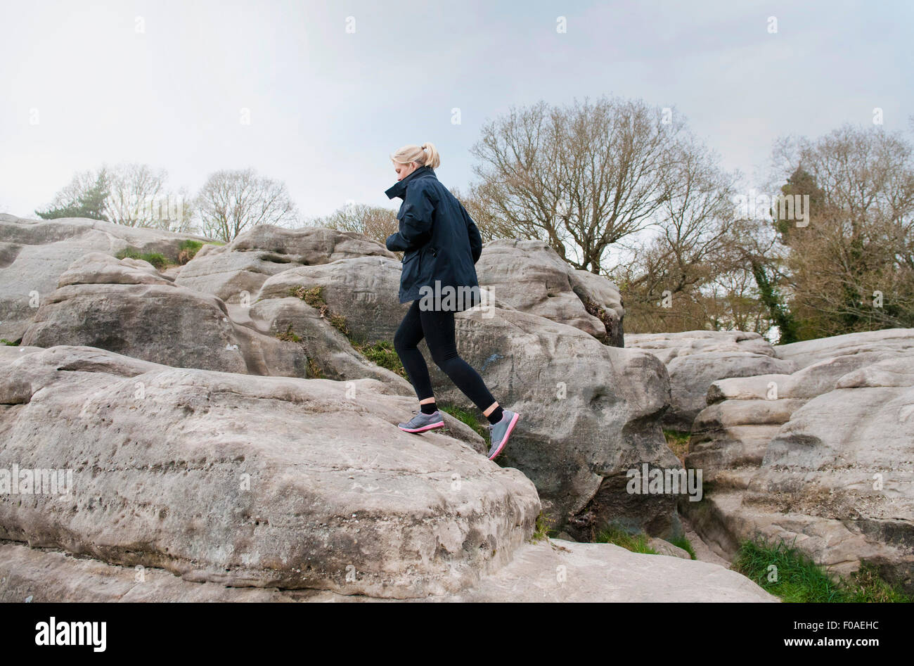 Mid adult female runner running up rock formation Stock Photo