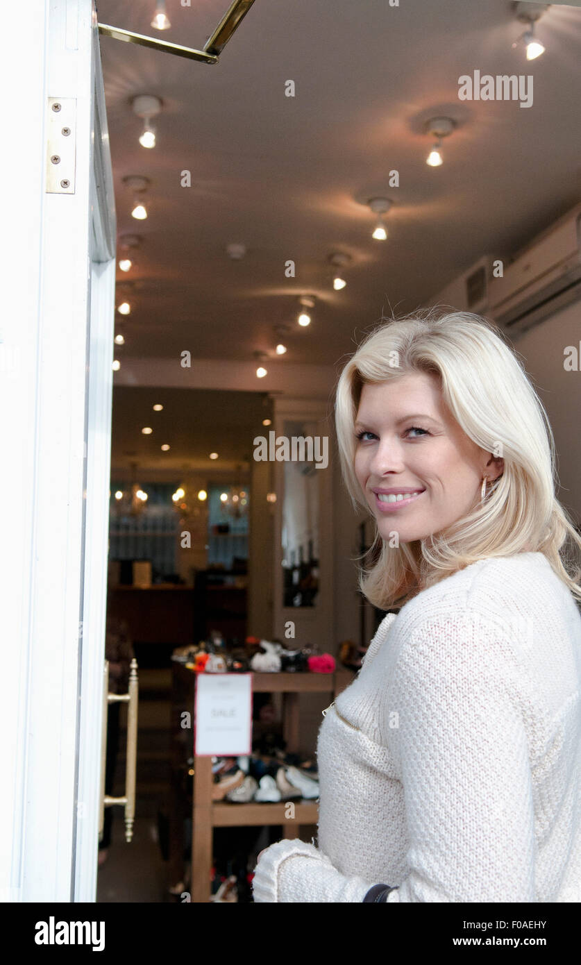 Mid adult woman looking over her shoulder in shop doorway Stock Photo