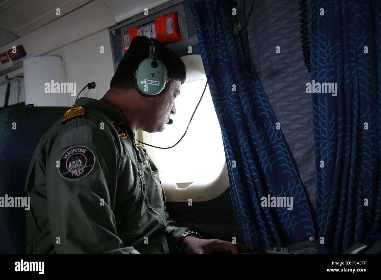 Port Louis. 10th Aug, 2015. A crew member of Mauritian Coast Guard conducts search operations over the surrounding waters of Mauritius on Aug. 10, 2015. The Indian Ocean nation of Mauritius, which is located 190 kilometers northeast of La Reunion, pledged to continue search operations for the missing Malaysia Airlines MH370 in its waters, Deputy Prime Minister Xavier-Luc Duval told Xinhua Monday. Credit:  Pan Siwei/Xinhua/Alamy Live News Stock Photo