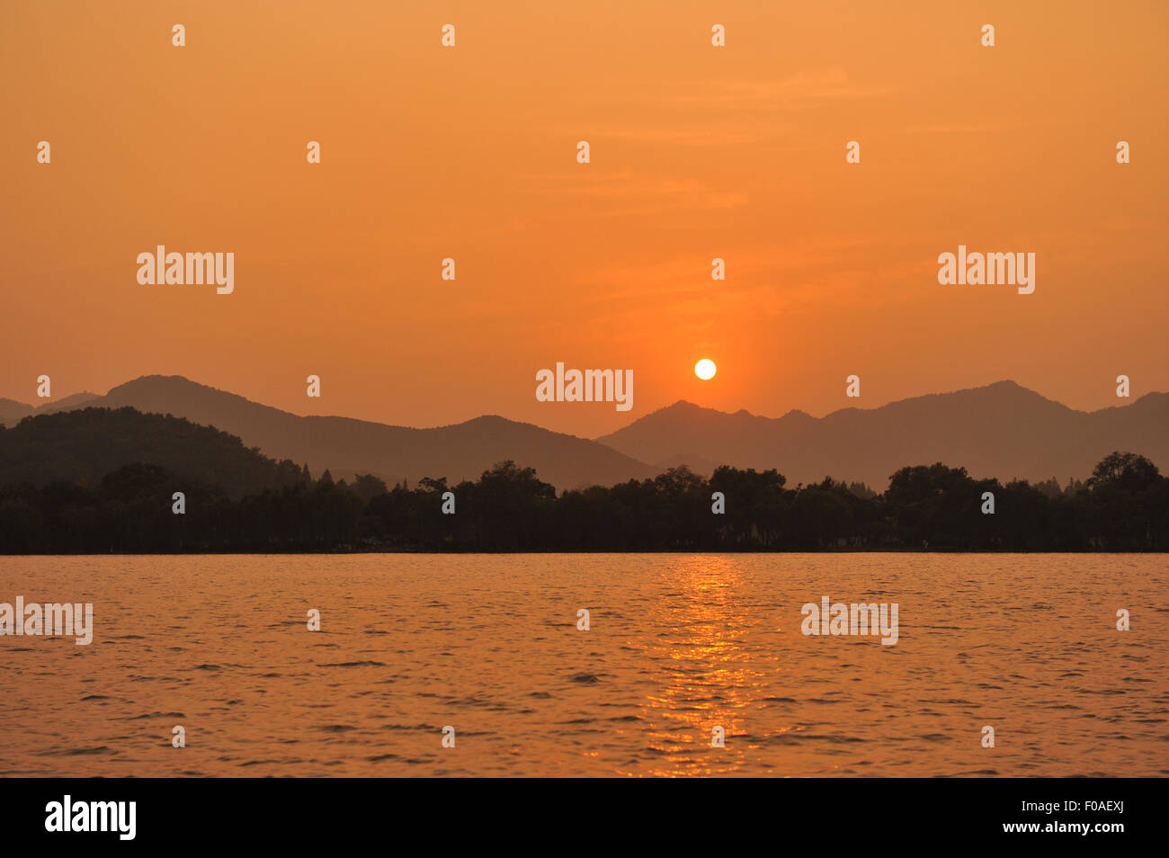 Sunset over lake, mountains in distance, Hangzhou, China Stock Photo