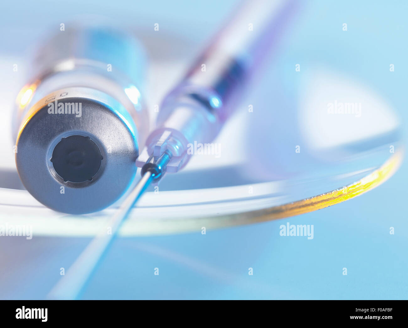 Vaccine and hypodermic syringe sitting on a glass dish Stock Photo