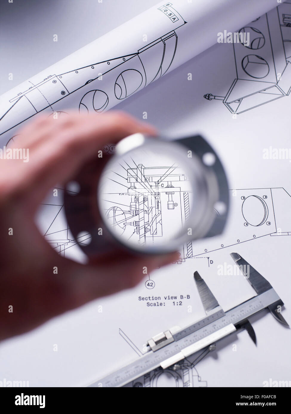Engineer holding a precision made component over a technical drawing with a dial caliper Stock Photo
