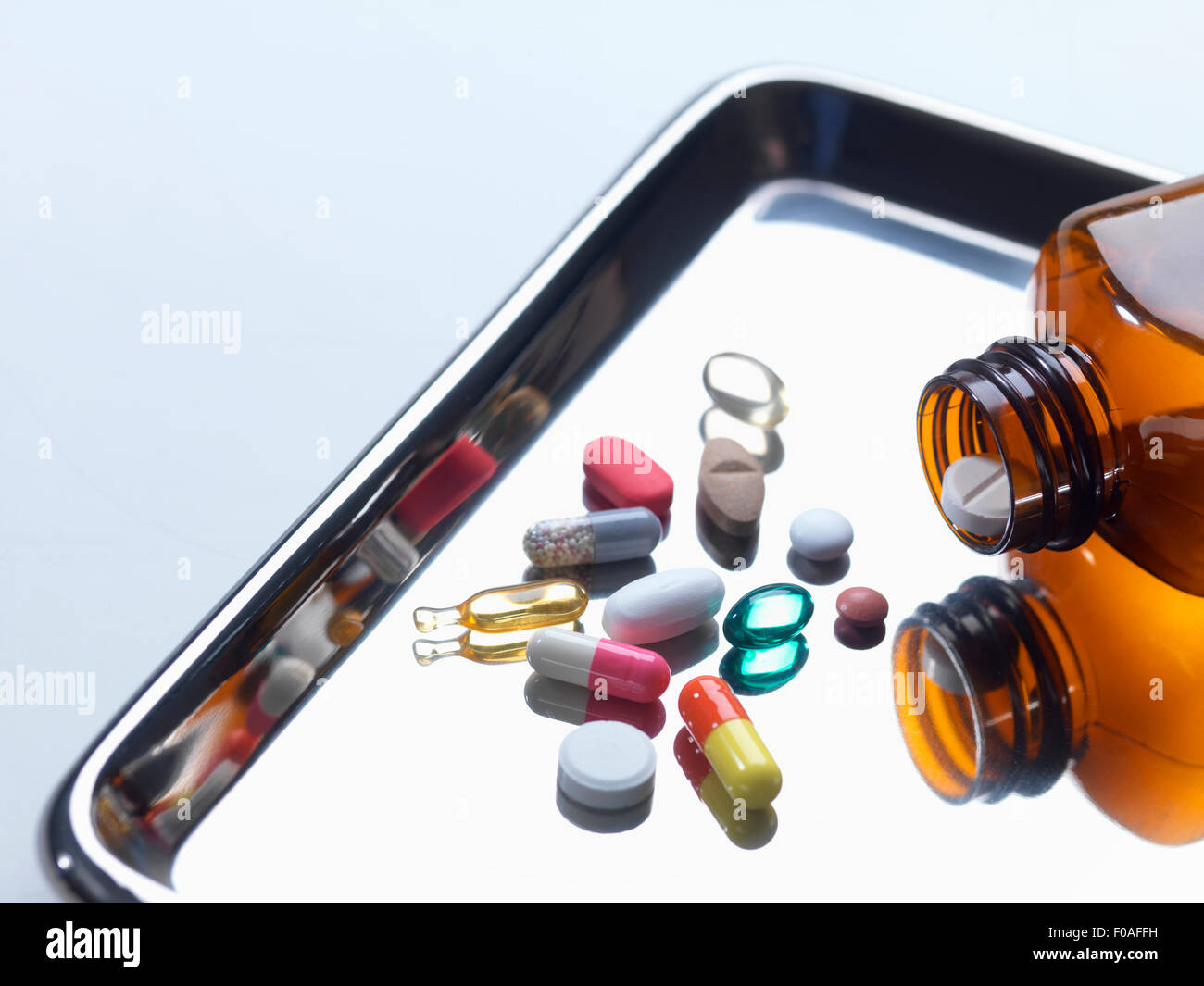 Close up of variety of medical drugs pouring from pill bottle on surgical tray Stock Photo