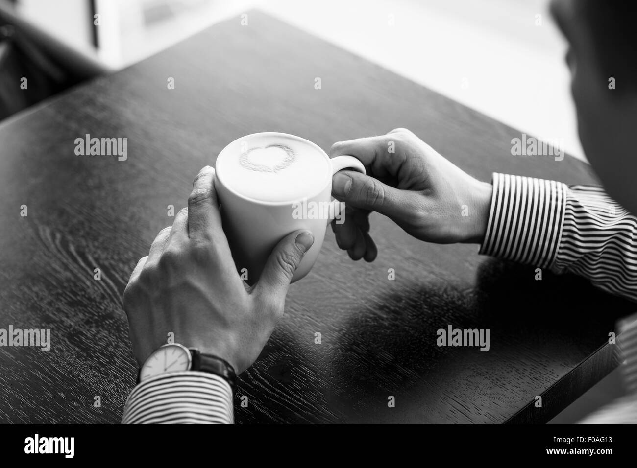 Businessman taking a break at the office as he enjoys a cup of hot aromatic coffee, close up view of his hands Stock Photo