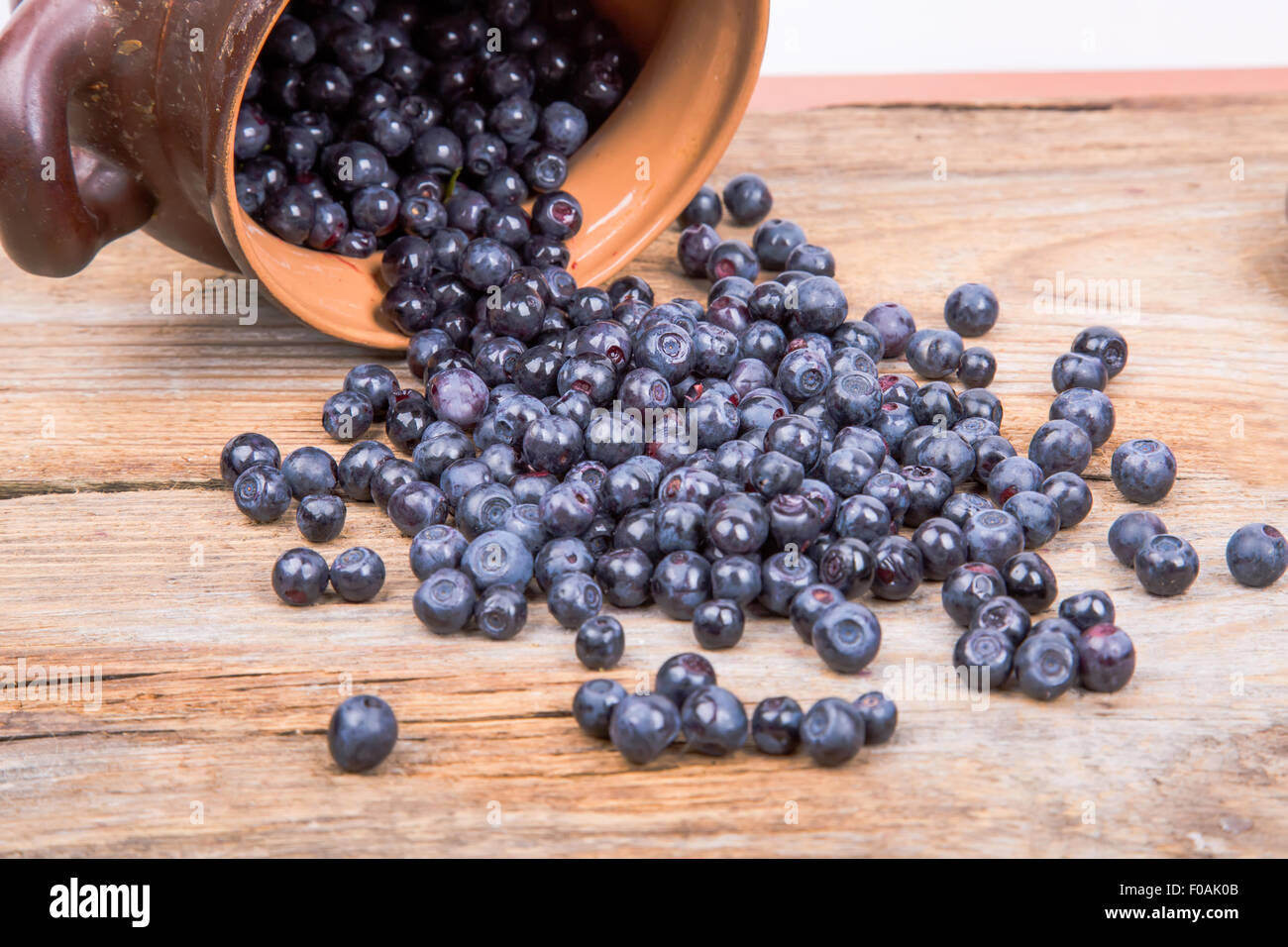 blueberry or raspberry scattered from pot over wooden background ...