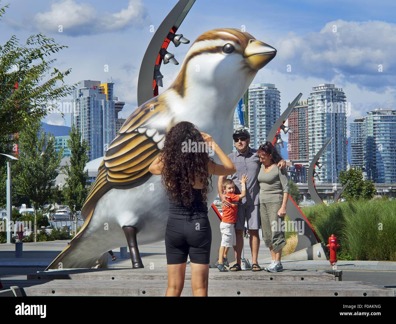 Two women sitting besides giant bird statue in Olympic Village