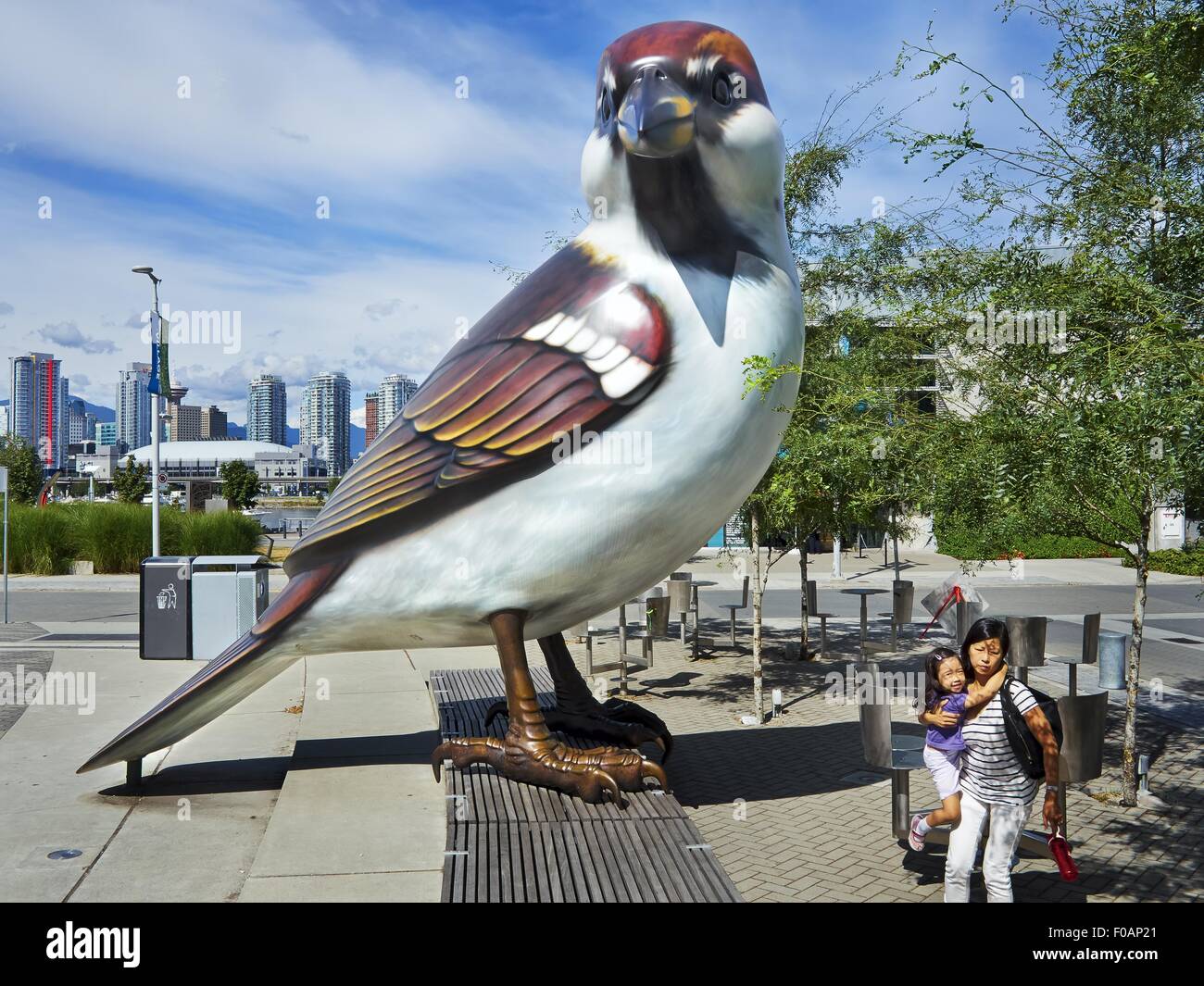 Two women sitting besides giant bird statue in Olympic Village