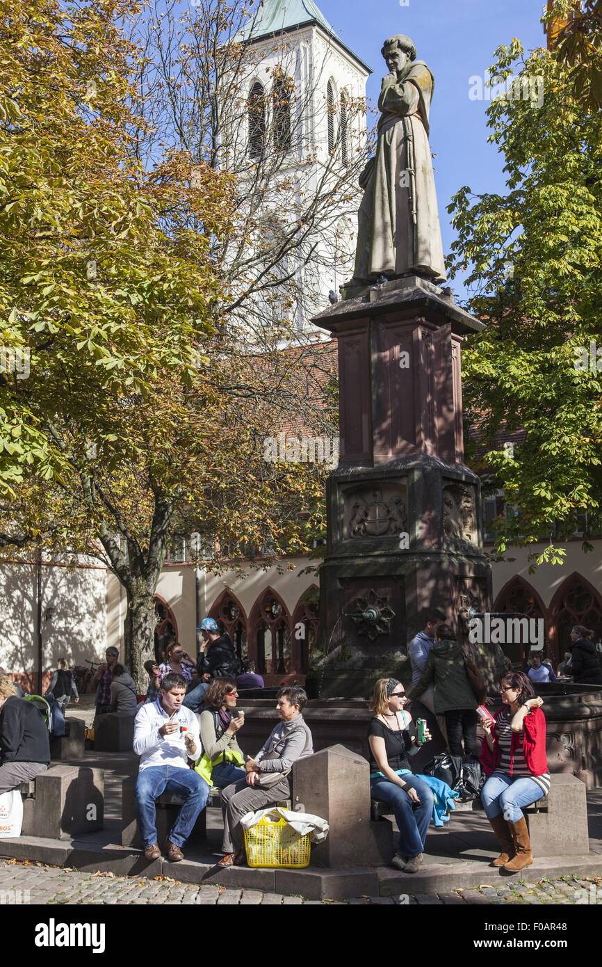People sitting around Berthold Schwarz Fountain in Town Hall square, Freiburg, Germany Stock Photo
