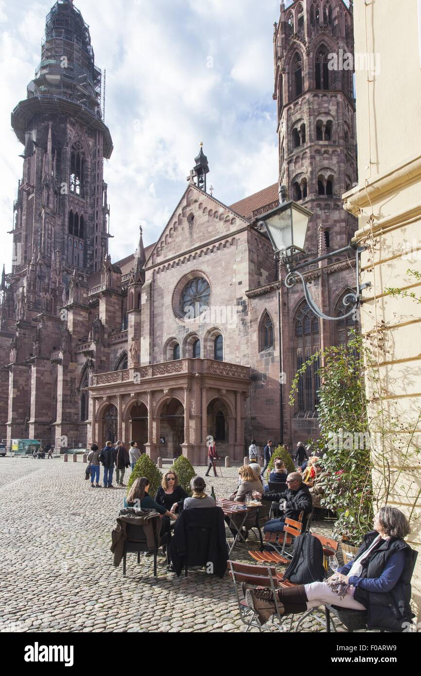 People sitting at cathedral square centre of old city, Freiburg, Germany Stock Photo