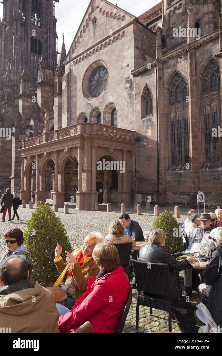 People sitting at cathedral square centre of old city, Freiburg, Germany Stock Photo