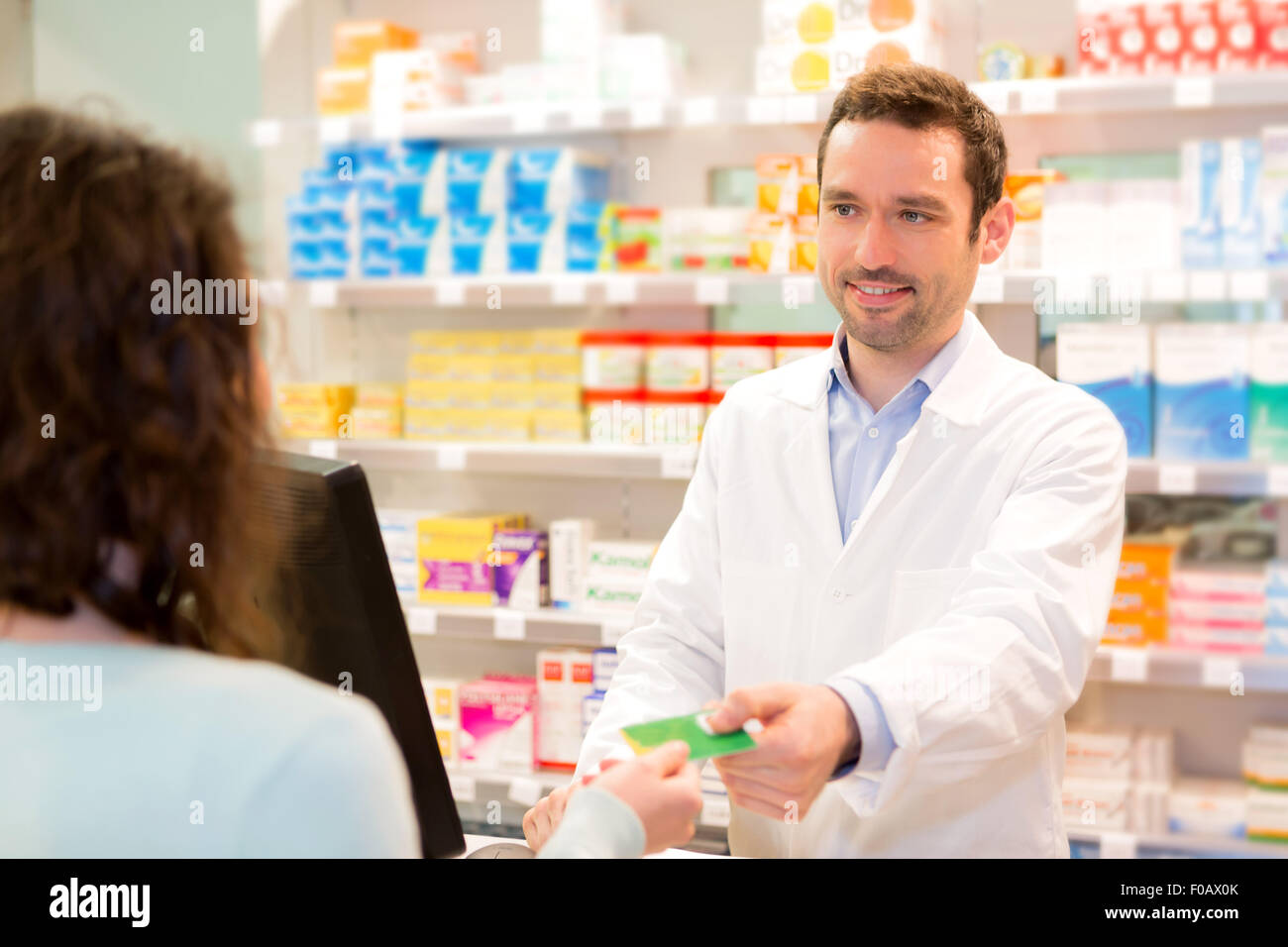 View of an Attractive pharmacist taking healt insurance card Stock