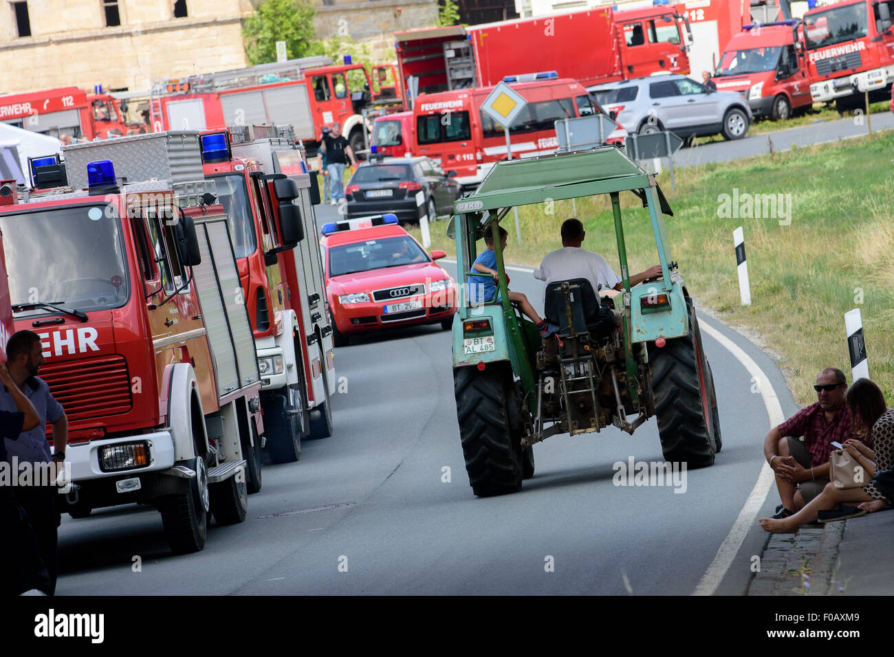 Engelmannsreuth, Germany. 11th Aug, 2015. A farmer drives past several fire engines in Engelmannsreuth, Germany, 11 August 2015. An F-16 fighter aircraft of the US Air Force crashed near Engelmannsreuth. Photo: NICOLAS ARMER/dpa/Alamy Live News Stock Photo