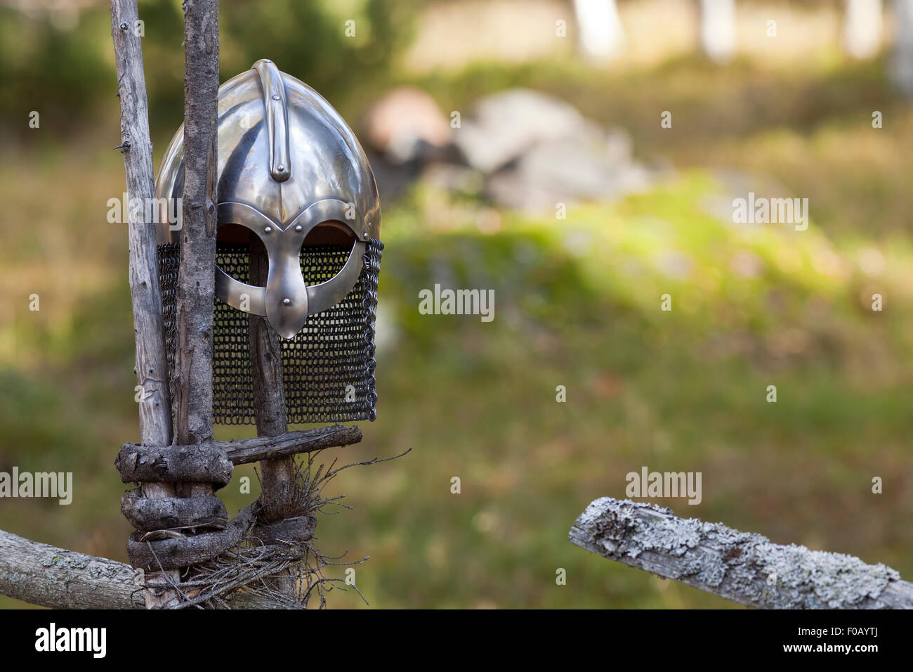 Steel Viking Knight helmet hangs on an old traditional wooden fence. Fuzzy background. Retro. Stock Photo