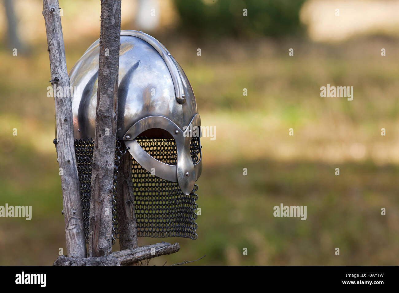 Steel Viking Knight helmet hangs on an old traditional wooden fence. Fuzzy background. Retro. Stock Photo