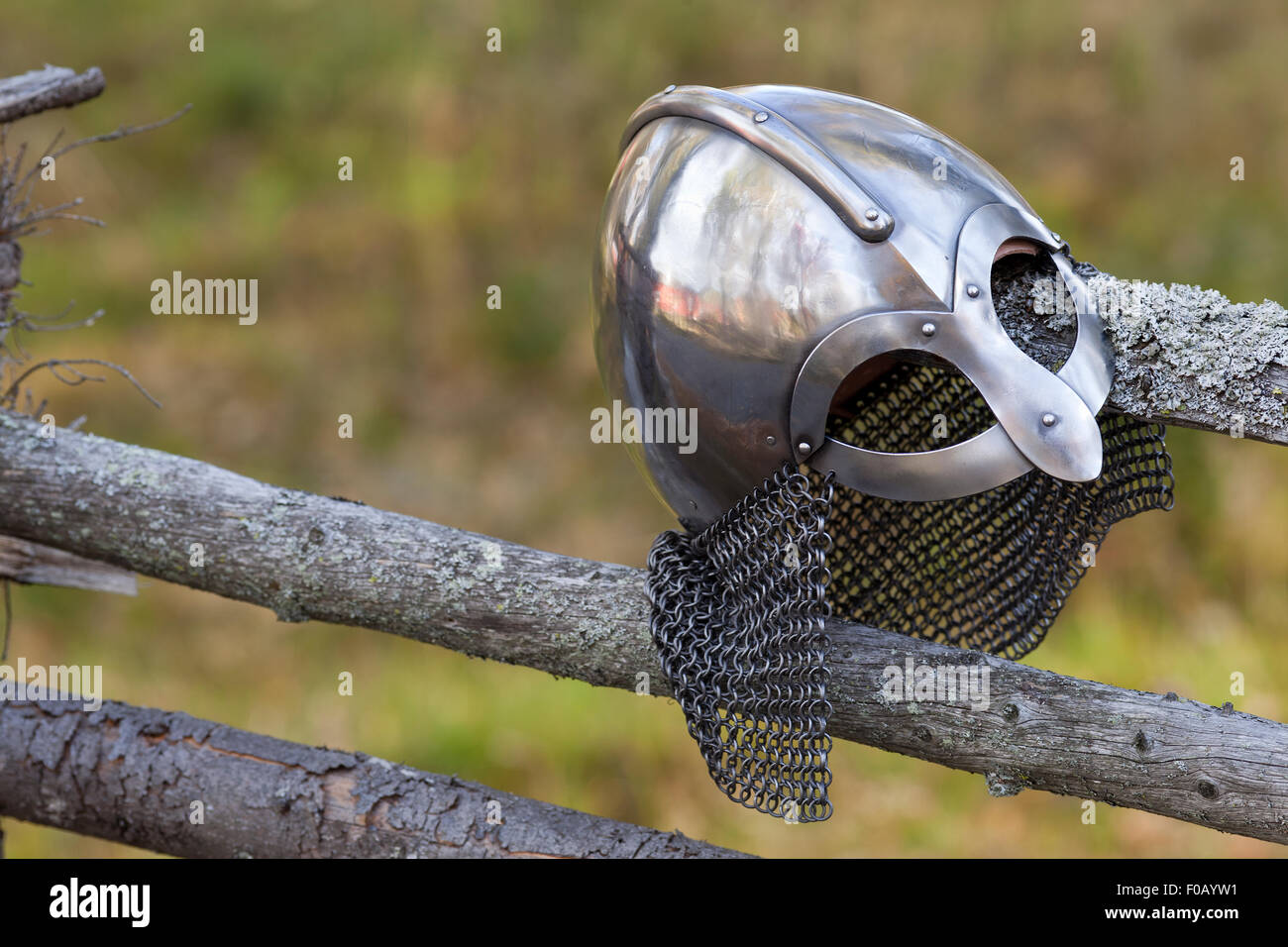 Steel Viking Knight helmet hangs on an old traditional wooden fence. Fuzzy background. Retro. Stock Photo