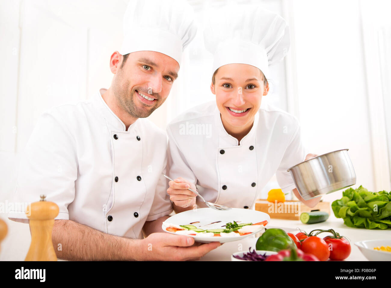 View of Young attractives professionals chefs cooking together Stock Photo