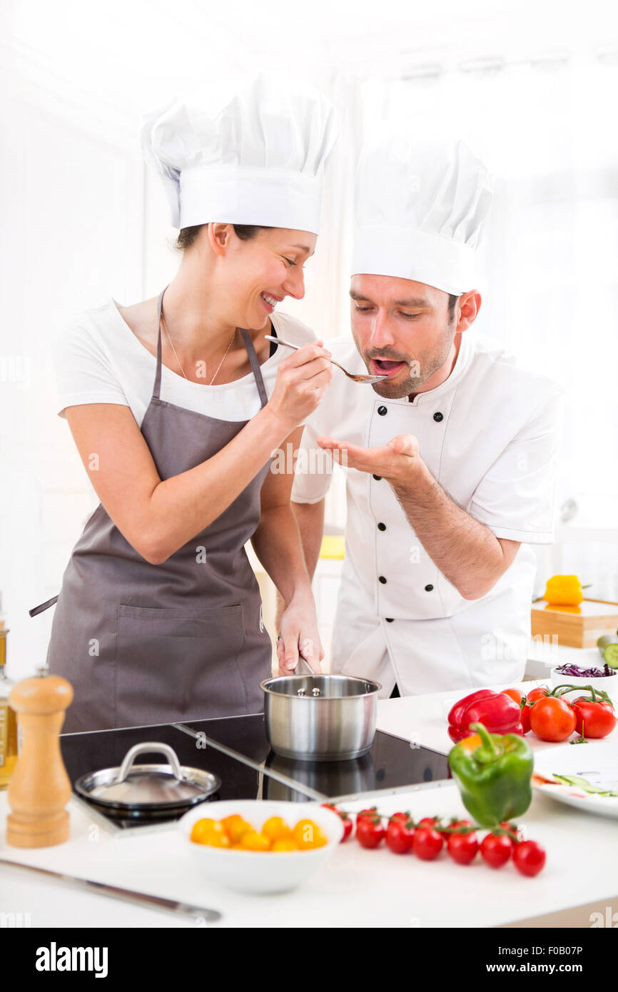 View of a Young chef training a young attractive girl to cook Stock Photo